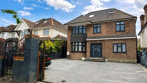 A residential area with a paved driveway, a gated entrance, and houses with brick facades and multiple windows. - Wembley Park - Free Parking (London)