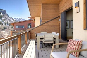 A wooden deck with outdoor furniture, a view of a mountain, and a building in the background. - Riverwood Ten Lux Poolside Ski In/Out to BC Westin Resort Amenities (Avon)