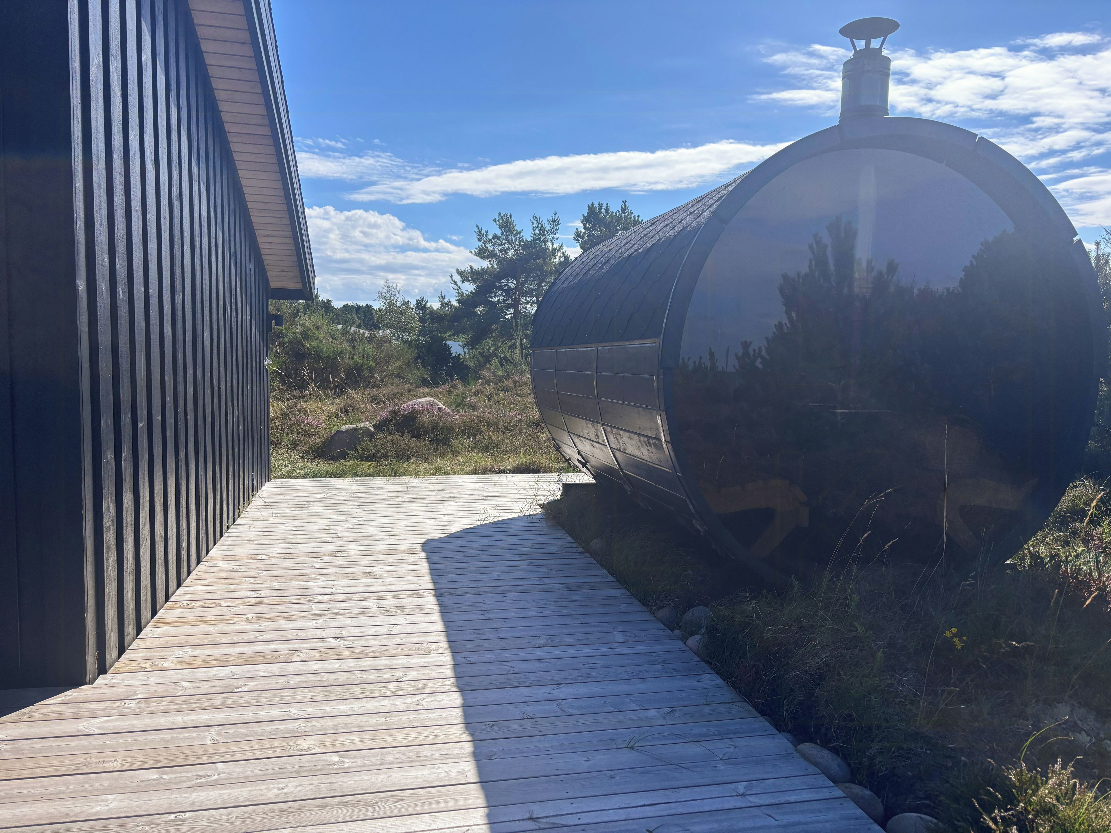 Una terraza de madera que conduce a un edificio moderno con una estructura cilíndrica.