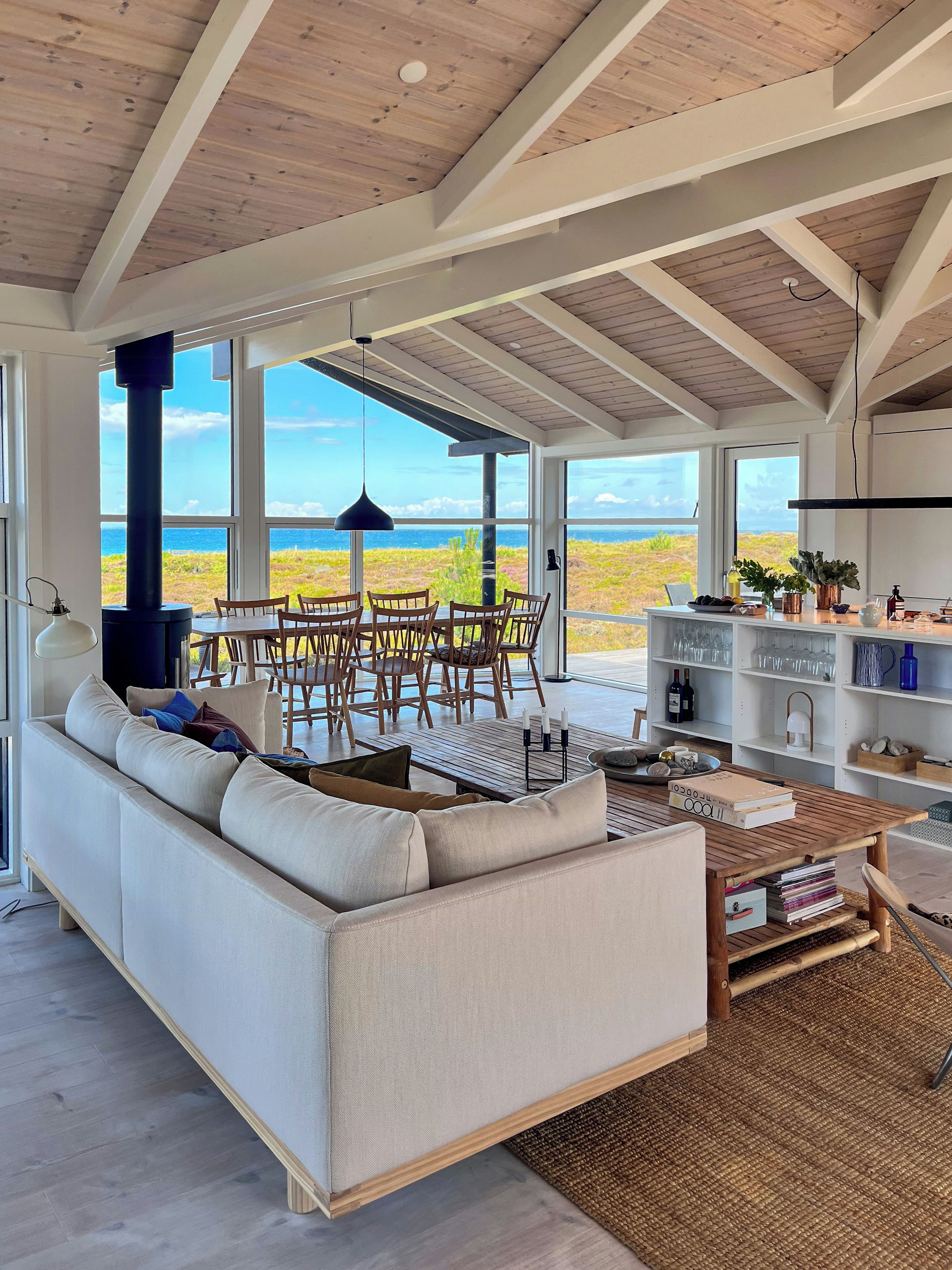 A spacious living area with a large sofa, dining table, and chairs, overlooking a scenic view.