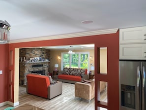 A living room with a stone fireplace, red sofas, and a kitchen with stainless steel appliances.