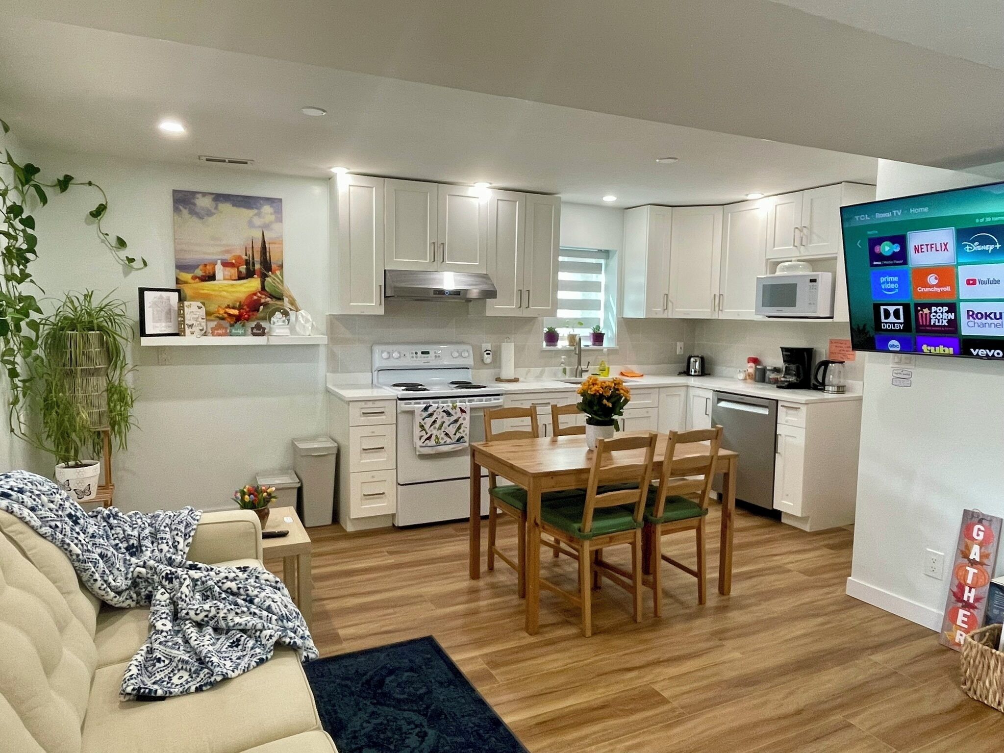 A modern kitchen with white cabinets, a built-in microwave, and a dining area with a wooden table and chairs.
