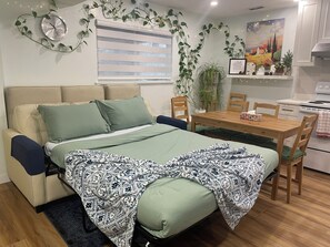Ein gemütlicher Wohnraum mit Schlafsofa, Esstisch und Küchenzeile.