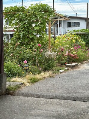 A garden with various plants and flowers, a wooden bench, and a lamp post. - Family-Friendly 2 Bedroom Sweethome Sleeps 6 + Free Parking (Vancouver)