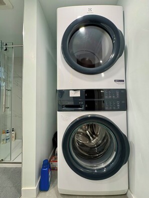 A front-loading washing machine with a control panel and a dryer stacked on top. - Family-Friendly 2 Bedroom Sweethome Sleeps 6 + Free Parking (Vancouver)