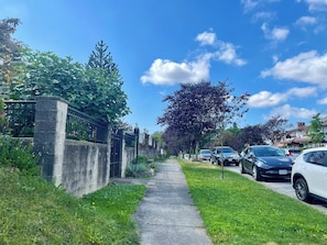 A residential street with parked cars, a sidewalk, and greenery. - Family-Friendly 2 Bedroom Sweethome Sleeps 6 + Free Parking (Vancouver)