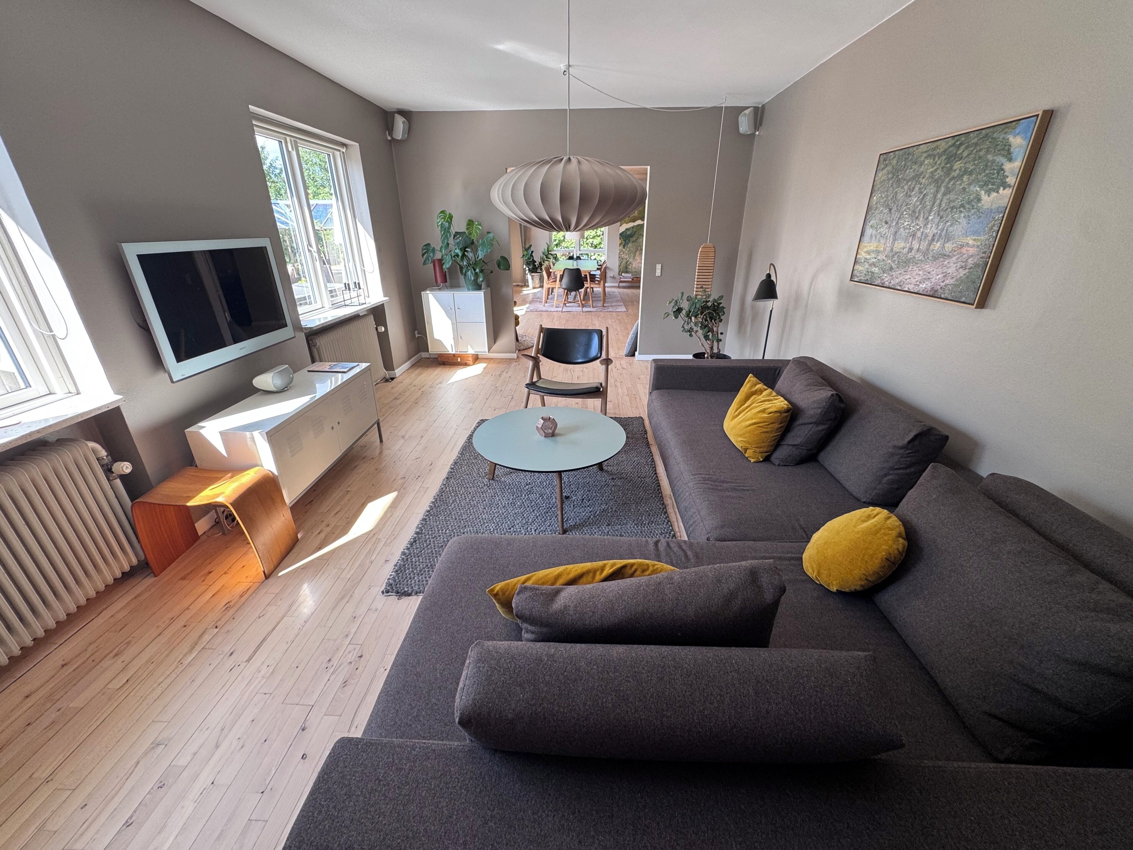 Un salon moderne avec un canapé gris, une table basse ronde et un téléviseur à écran plat.