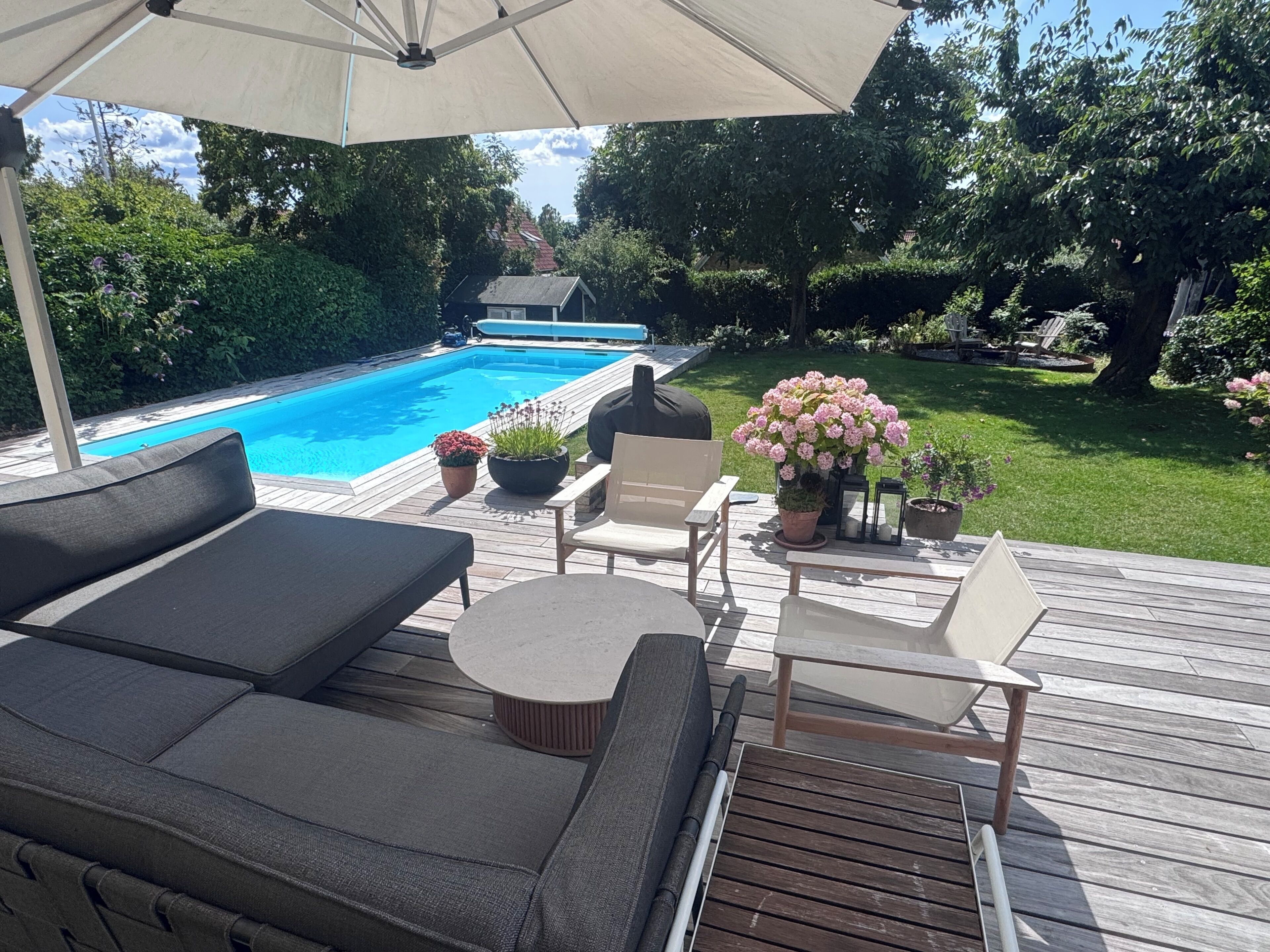 Une terrasse dotée de mobilier d’extérieur, d’une piscine et de plantes en pot.
