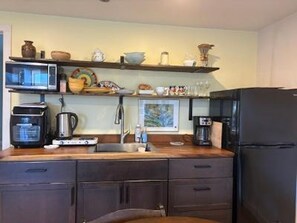A compact kitchen with a microwave, coffee maker, and a refrigerator.