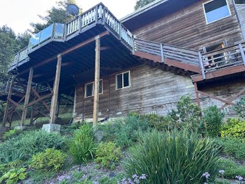 A rustic wooden building with a balcony and a garden in front.