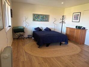 A bedroom with a bed, a wooden dresser, a radiator, and a floor lamp.