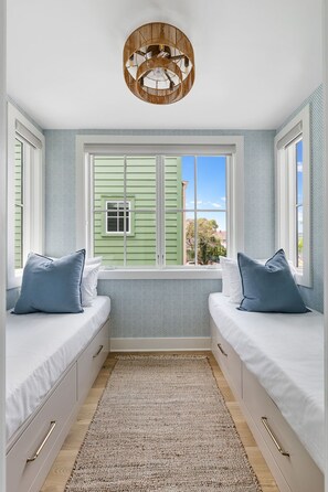 A room with two beds, a window with shutters, a woven ceiling light fixture, and a patterned wall. - Signature Residence @ Smalls Alley | Rooftop Deck (Charleston)