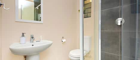 A bathroom with a pedestal sink, a toilet, and a glass-enclosed shower area.