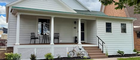 A single-story house with a porch, a front door, and a small staircase leading to the entrance.
