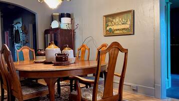 Un comedor con mesa de madera, sillas, una lámpara de araña y un cuadro en la pared.