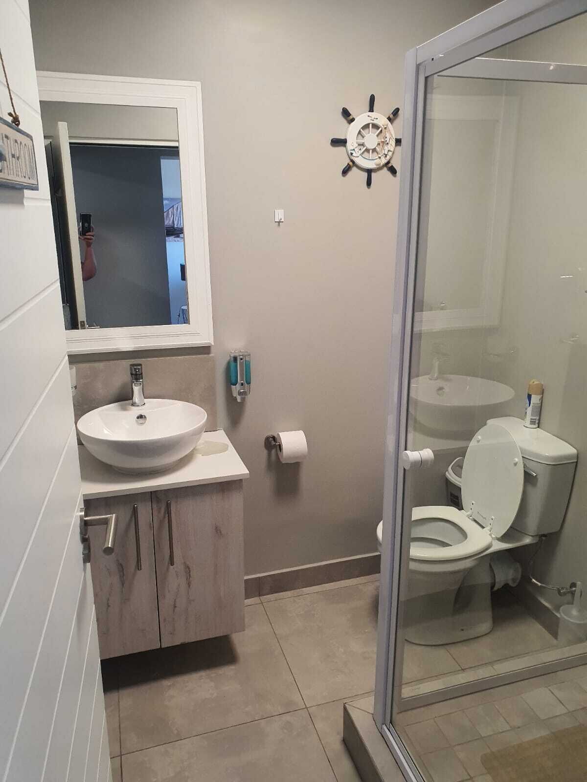 A bathroom with a white sink, a toilet, and a glass shower enclosure.
