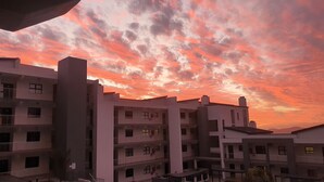 A multi-story building with balconies, a swimming pool, and a sunset sky. - Modern 2-bedroom apartment in Langebaan near the beach (Langebaan)