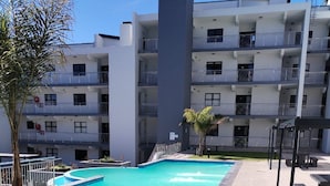 A modern apartment building with a swimming pool and outdoor seating area. - Modern 2-bedroom apartment in Langebaan near the beach (Langebaan)