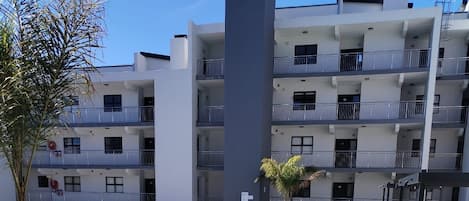 A modern apartment building with a swimming pool and outdoor seating area.