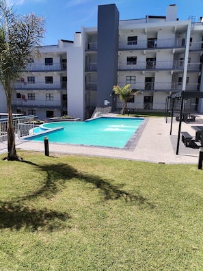 Ein modernes Mehrfamilienhaus mit Schwimmbad und Außenbereich mit Sitzgelegenheiten.