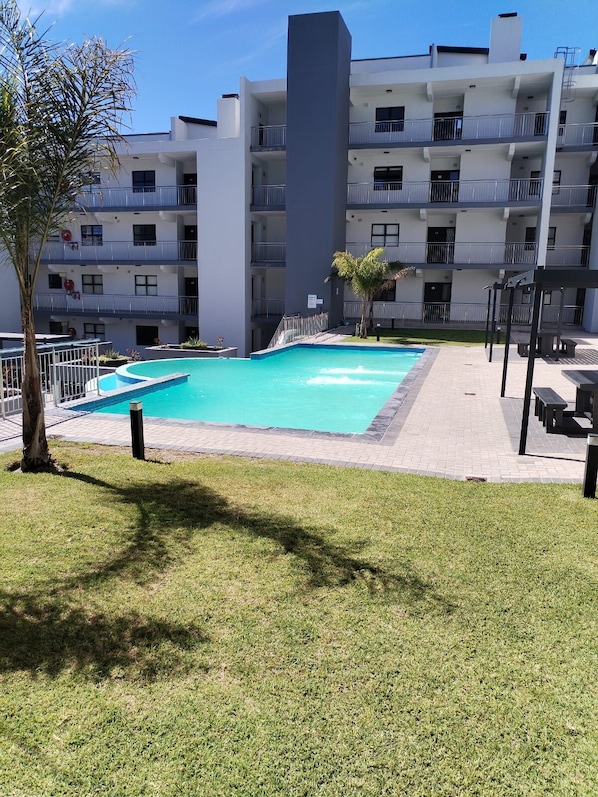Un moderno edificio de apartamentos con piscina y zona de estar al aire libre.