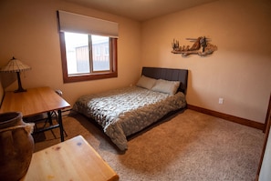 Une chambre à coucher avec un lit, une table, une lampe et une fenêtre.