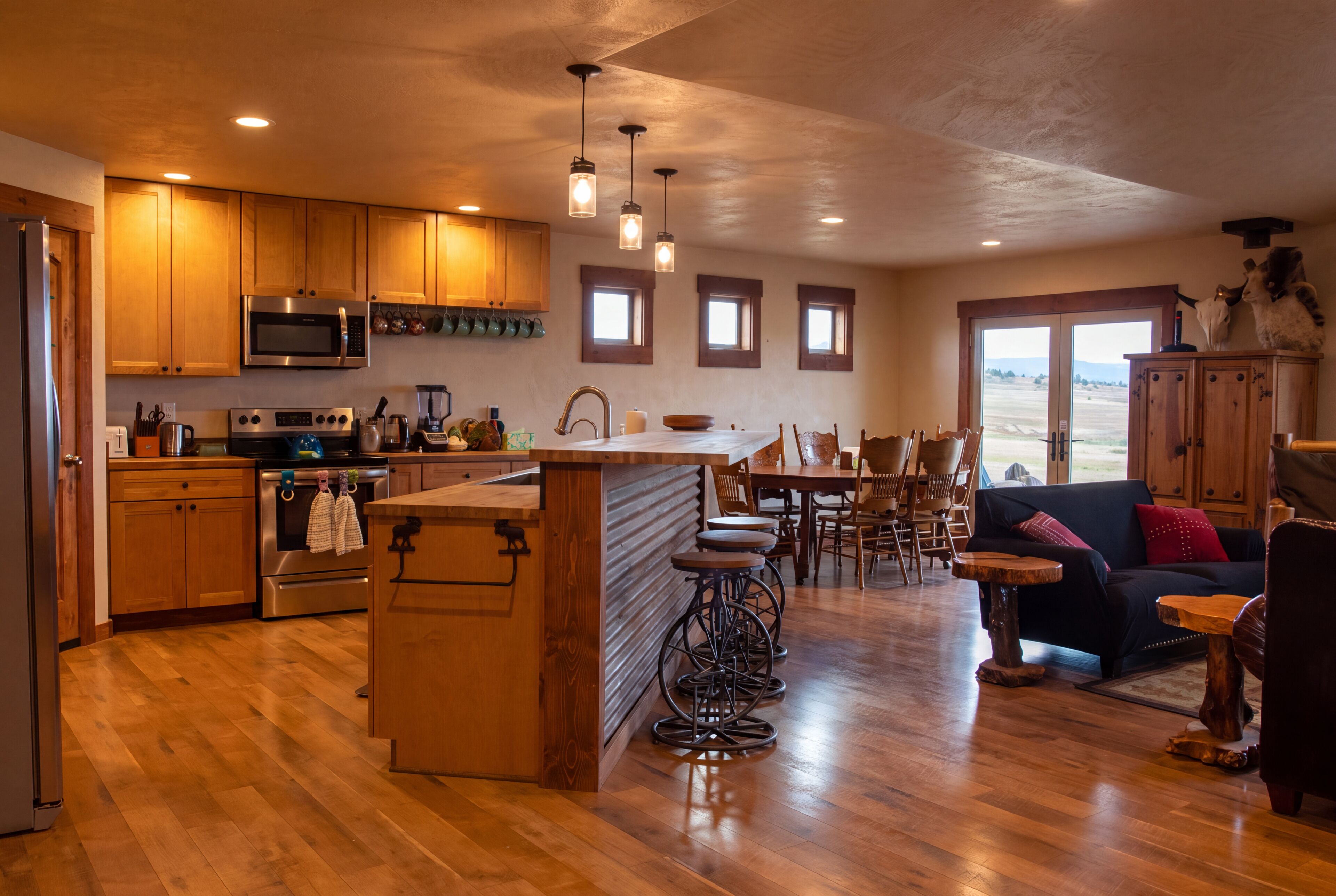A spacious kitchen with wooden cabinets, a stainless steel microwave, and a large island with stools.