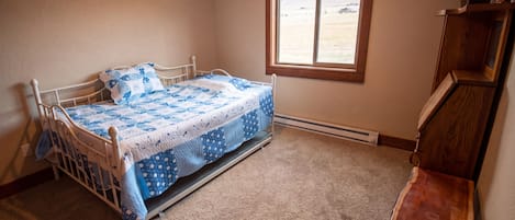 A bedroom with a bed, a window, and a wooden dresser.