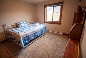 Ein Schlafzimmer mit einem Bett, einem Fenster und einer Holzkommode.