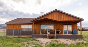 A wooden cabin with a covered porch, large windows, and a grill area. - Ennis Montana Cabin - Madison Range Views - 5 minutes to the Madison River (Ennis)