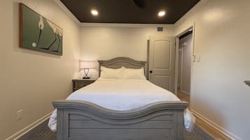 A hotel room with a bed, a nightstand, a ceiling fan, and a door.