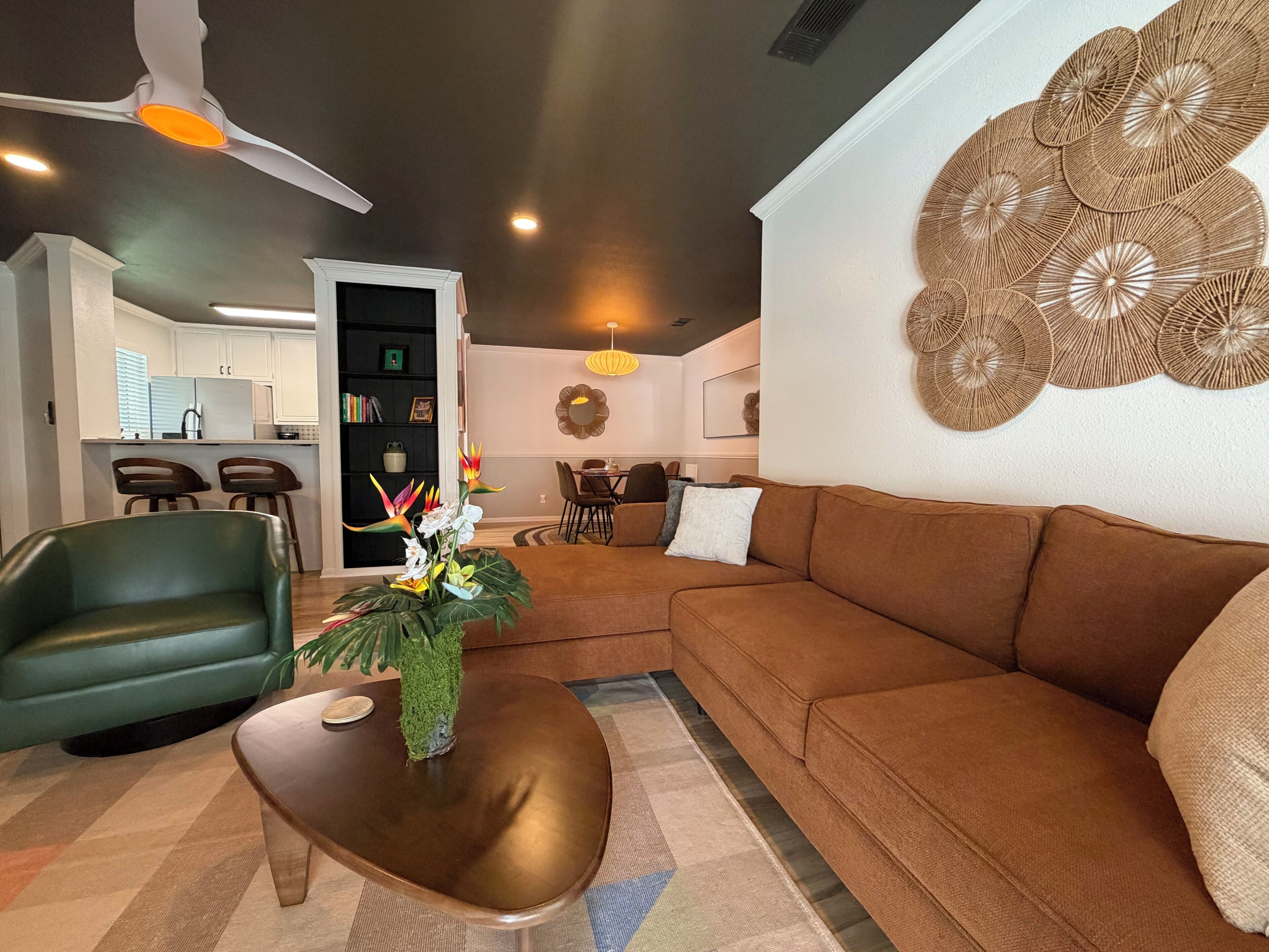 Ein modernes Wohnzimmer mit einem Ecksofa, einem grünen Sessel, einem Couchtisch und einer Wanddekoration.