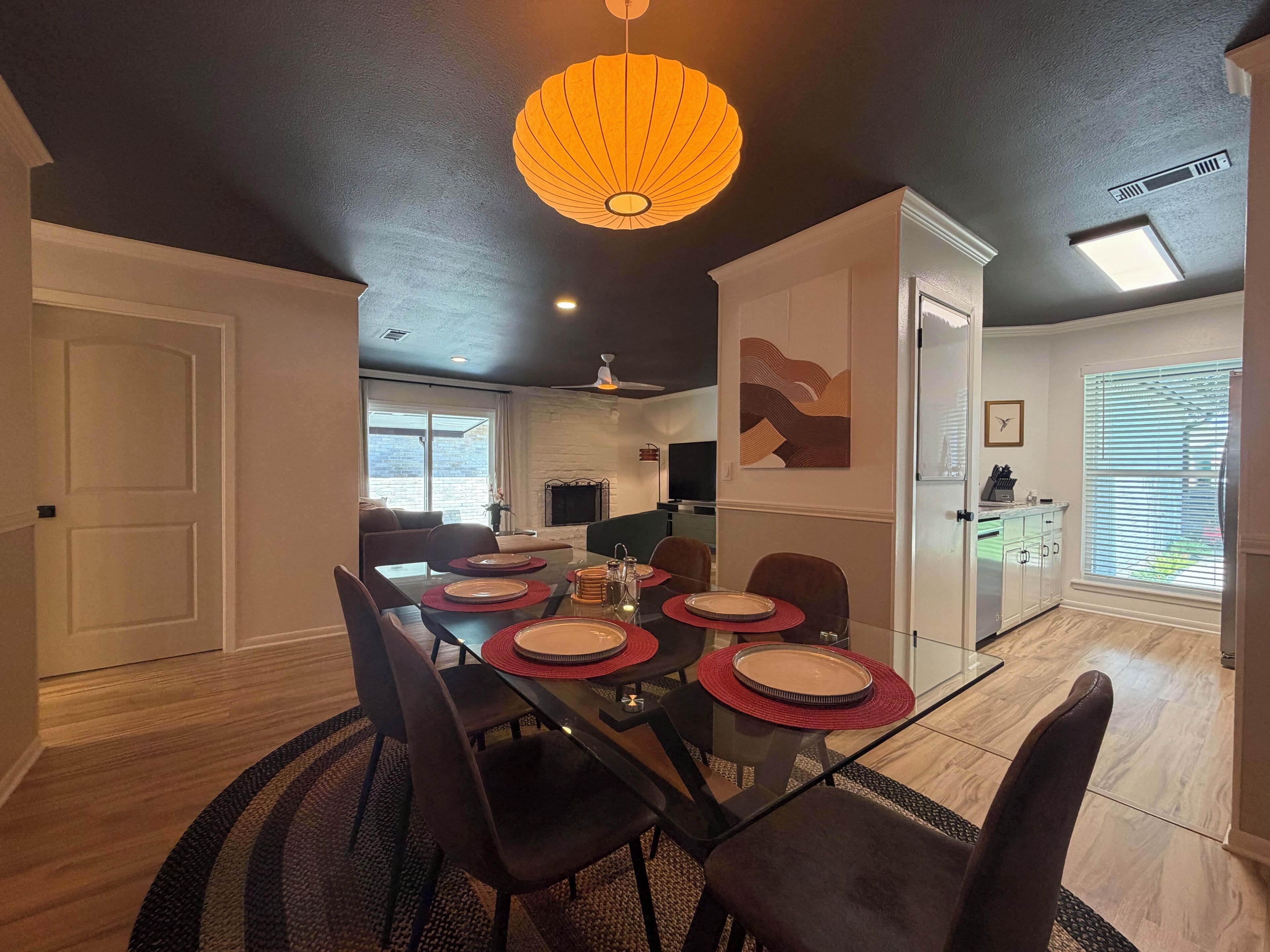 A dining area with a glass table, red placemats, and dark chairs.