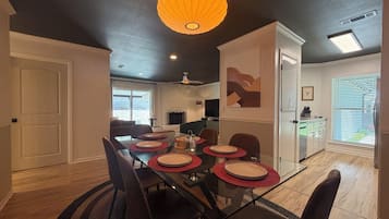 A dining area with a glass table, red placemats, and dark chairs.