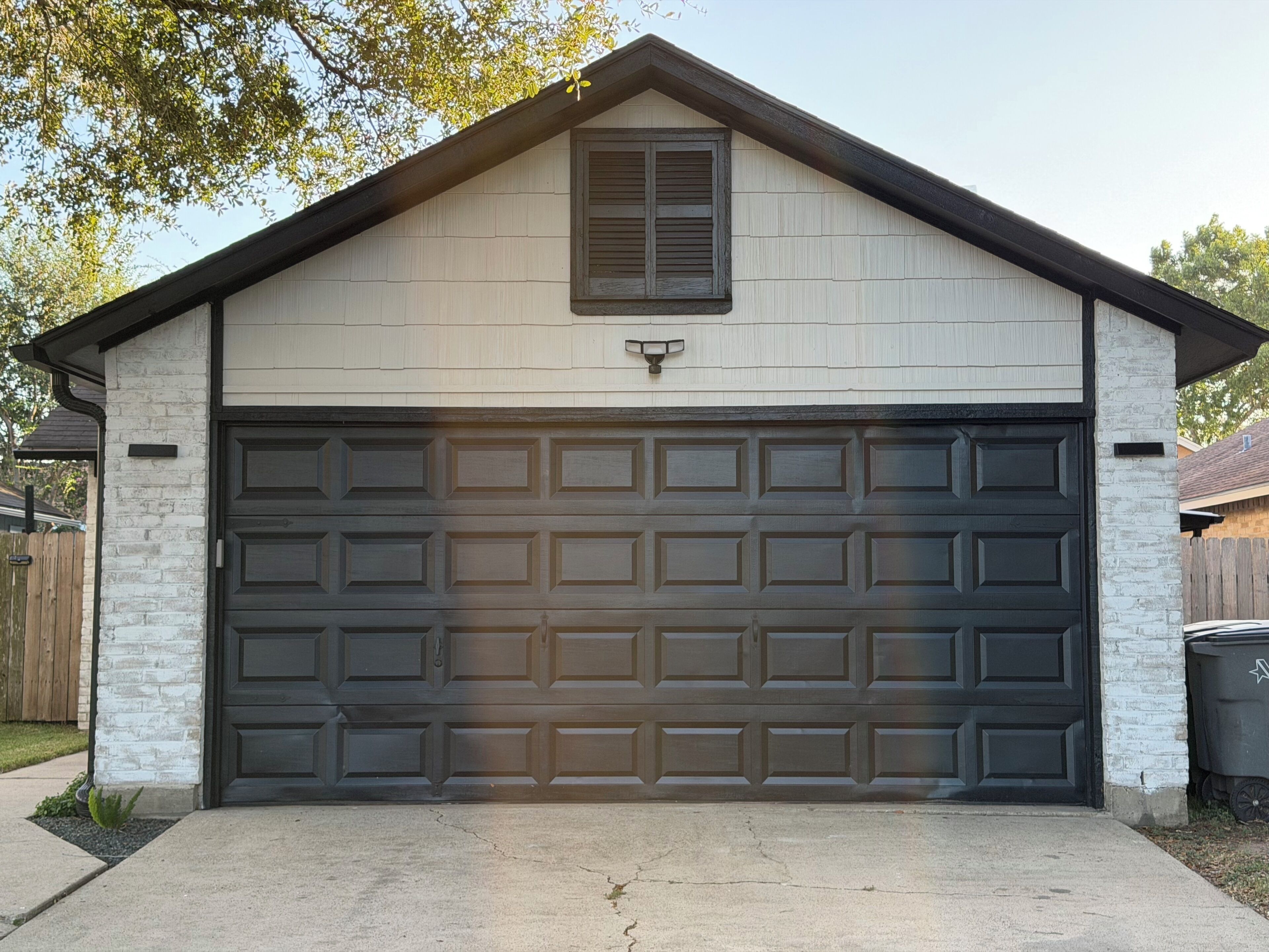 Ett garage med en mörk dörr, ett litet fönster och en ljusare fasad.