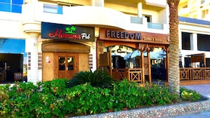 A building with a 'Havana Pub' and 'FREEDOM Coffee & More' on the ground floor. - Room-florenza Khamsin K203 Hurgada (Hurghada)