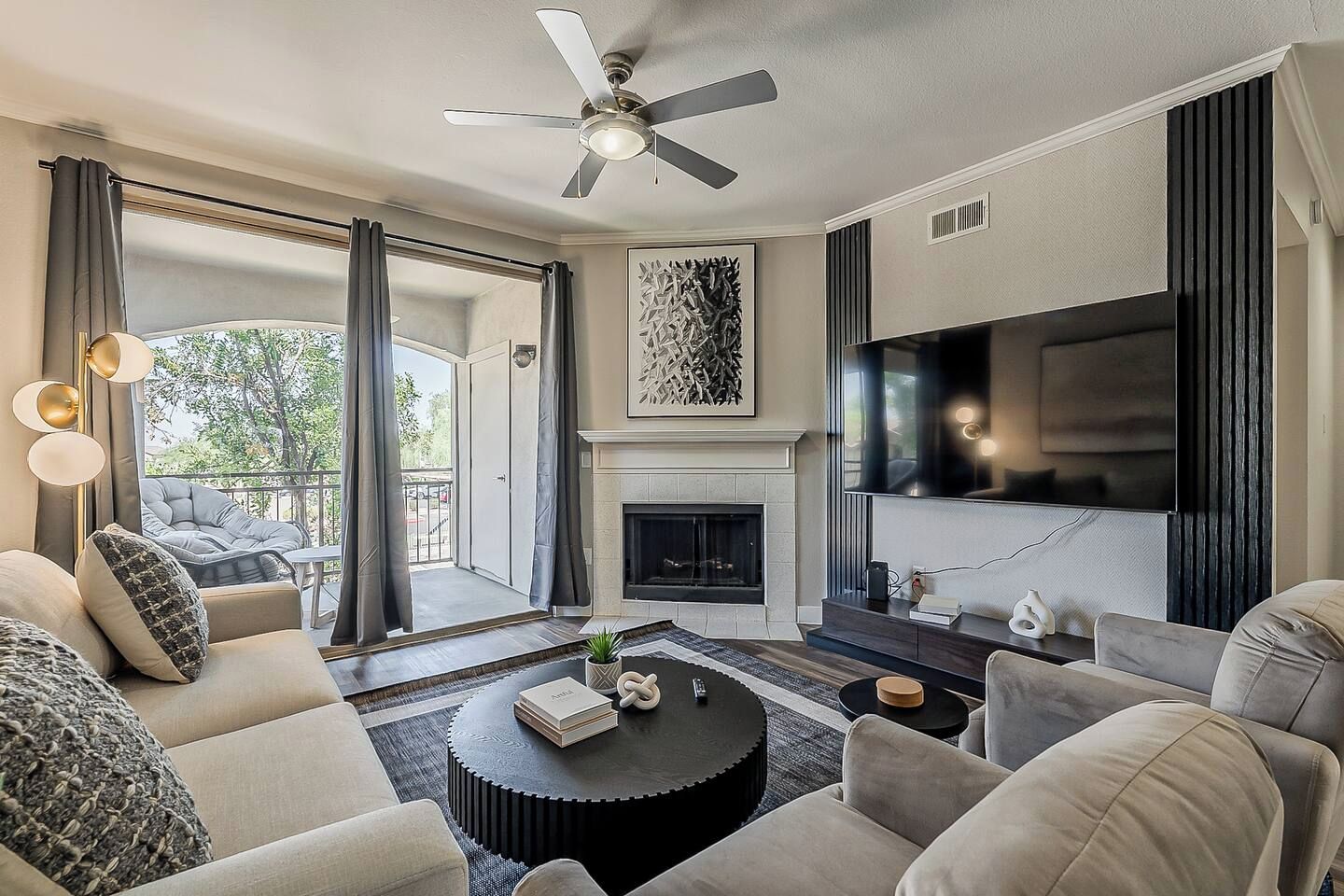 A modern living room with a fireplace, a flat-screen TV, and a ceiling fan.