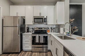 Eine moderne Küche mit Edelstahlgeräten, weißen Schränken und einem eingebauten Backofen.