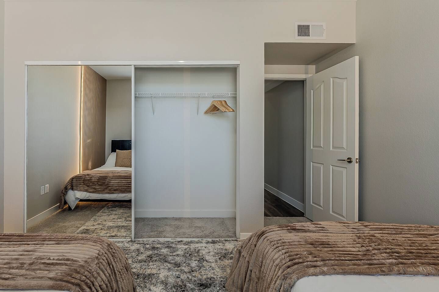 Ein Hotelzimmer mit einem Bett, einem Schrank und einer Tür zu einem weiteren Raum.
