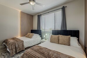 Habitación de hotel con dos camas, un ventilador de techo y una ventana con persianas.