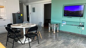 Eine moderne Küche mit einem runden Esstisch, Stühlen, einem Kühlschrank und einem an der Wand befestigten Fernseher.