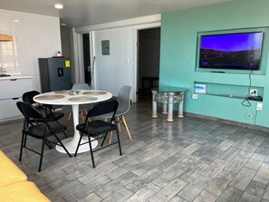 Una cocina moderna con una mesa redonda de comedor, sillas, un refrigerador y un televisor montado en la pared.