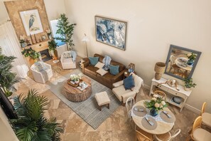 Een ruime woonkamer met een open haard, zitmeubelen en een eethoek met een ronde tafel.