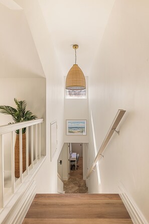A staircase with a wooden finish, white walls, and a hanging pendant light. - Luxe 3BR 3BA Condo 2 min walk to Lake & Loop Trail 4mi Hosp 10mi Beach 6mi Irv (Mission Viejo)