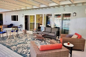 Un espace extérieur abrité, aménagé avec un sol à motifs, un canapé, un fauteuil et une petite table.