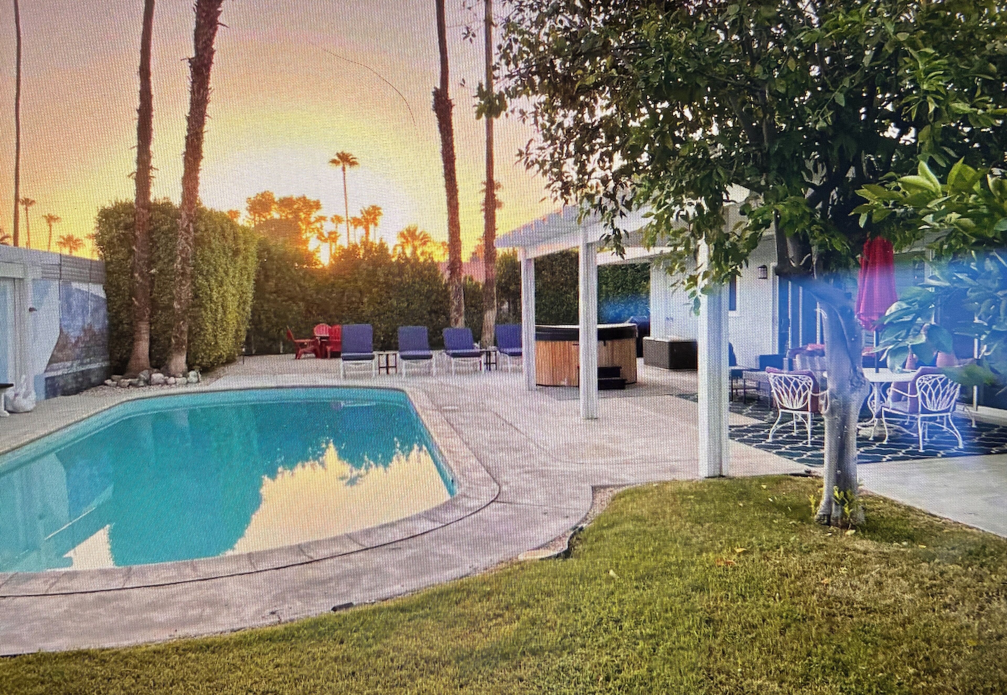 Una piscina con bordo circostante, sedie a sdraio e un'area salotto coperta.