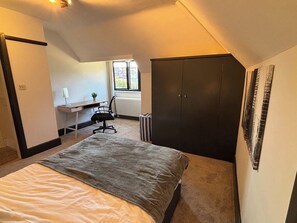 A bedroom with a bed, a desk, a chair, and a wardrobe. - Family beach escape with Pool (Bournemouth)