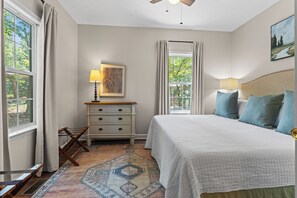 Een slaapkamer met een bed, nachtlampen, een kaptafel, een vloerkleed en een plafondventilator.