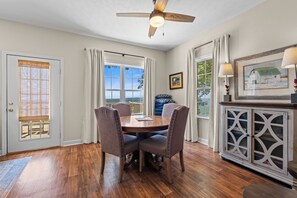 Ein Essbereich mit Holztisch und Stühlen, einem Deckenventilator und Blick durch das Fenster.