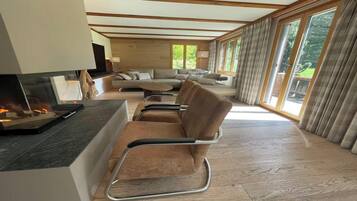 A modern living room with a fireplace, comfortable seating, and large windows.